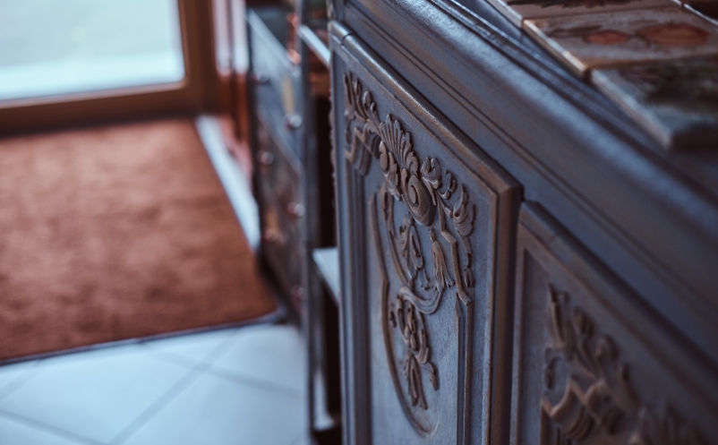 Close-up photo of hand-painted tiles on a vintage bookshelf.